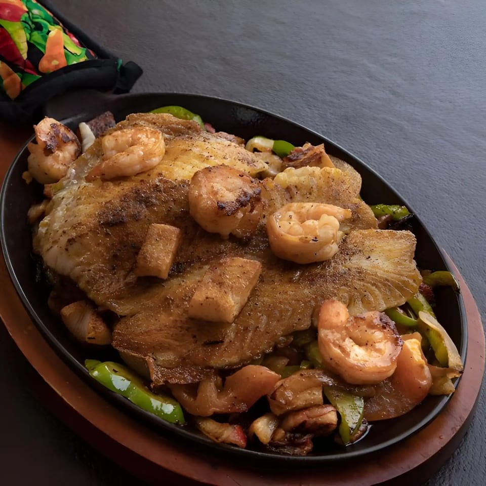 Dos Charros' sizzling fajita platter with tilapia, shrimp, green peppers, and onions.